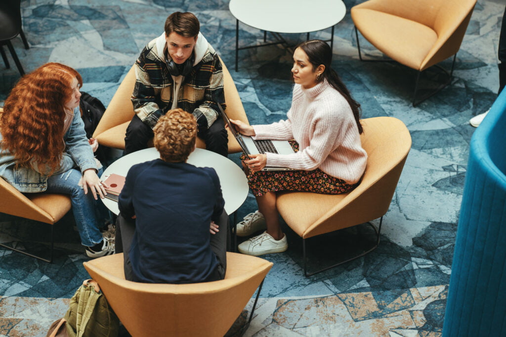 Tenåringer sitter ved et bord og jobber med et prosjekt.